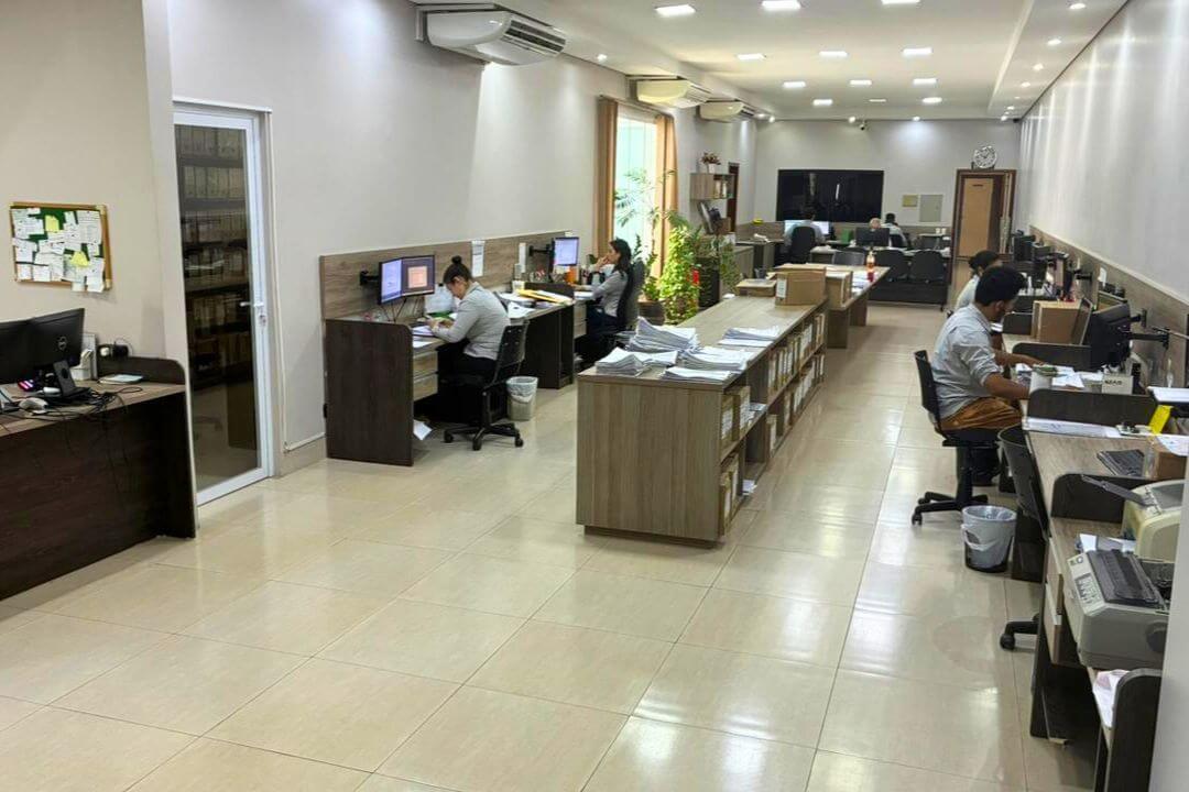 Corredor do escritório com armários de arquivo e profissionais focados na gestão contábil.